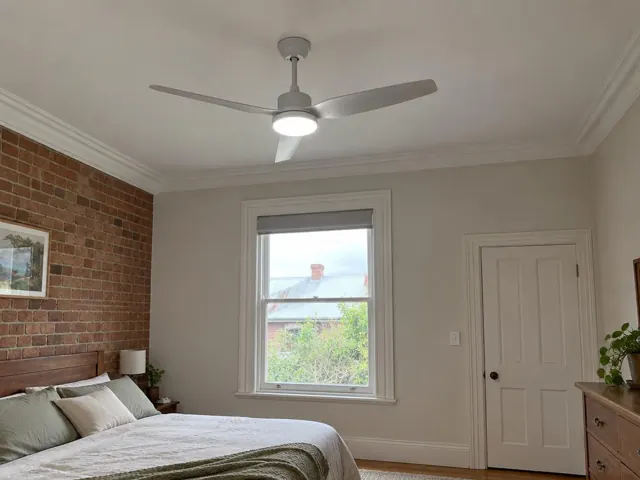 Ceiling fan installed in a bedroom with brick feature wall, window and white ceiling in Tighes Hill